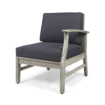 The Perla Armchair is a modern armless lounge chair featuring a weathered wooden frame and thick dark gray cushions on the seat and backrest, displayed against a white background.