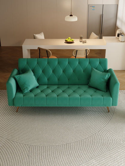 A modern living room features a green Convertible Double Folding Living Room Sofa Bed with two pillows on a textured circular rug. In the background, there's a white table with chairs, a bowl of apples, and a refrigerator.