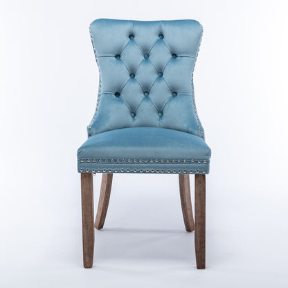 The Nikki set includes two modern, high-end tufted velvet dining chairs with solid wood legs and nailhead trim, featuring a curved backrest, shown in blue against a white background.