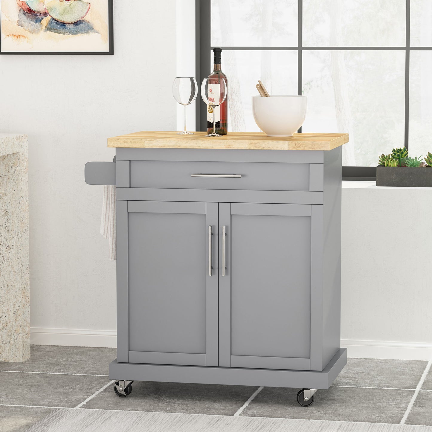 The Negley - Contemporary Kitchen Cart With Wheels in gray features a light wood top, drawer, two cabinet doors, silver handles, and a towel rack. A wine bottle, two glasses, and a white bowl sit on the cart.