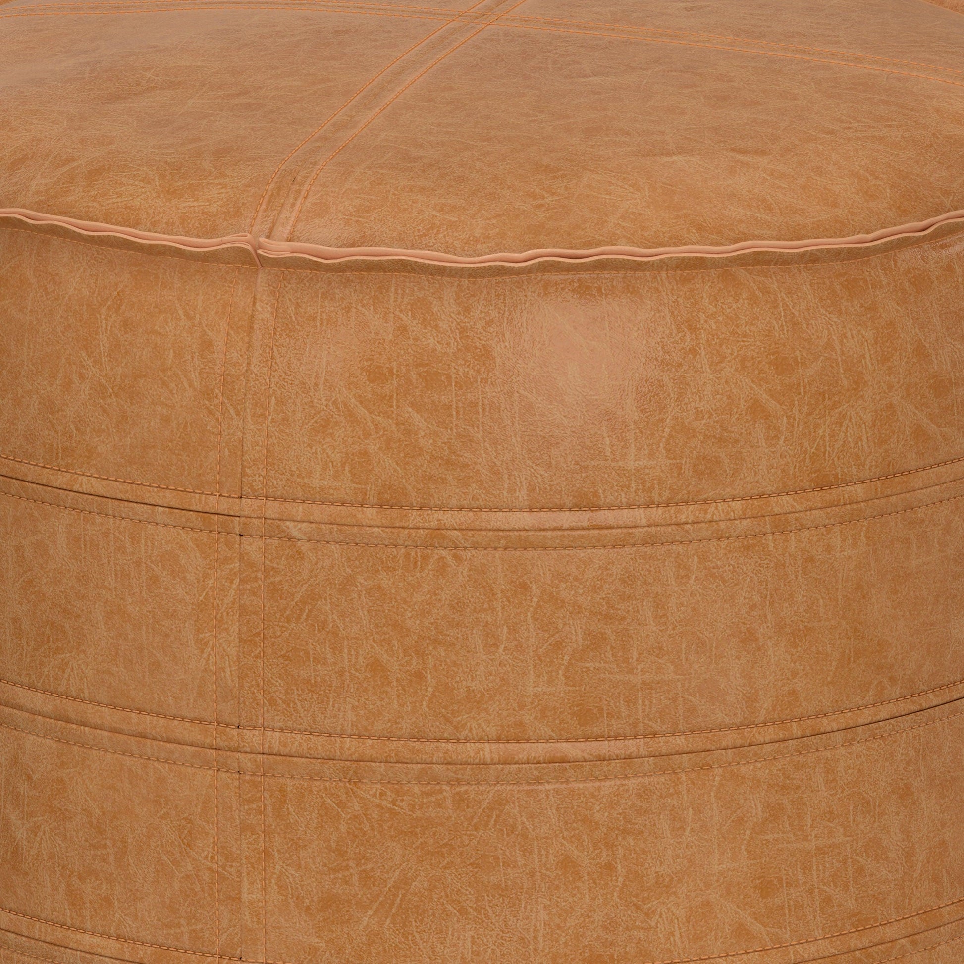Close-up of the Brody - Round Pouf, featuring tan leather with visible stitching and a smooth, textured surface. The image highlights the top and upper side, showcasing material and seam details.