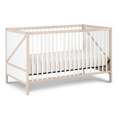 The Pixie Zen - 3-in-1 Crib in walnut features a minimalist design with light wood, white slats and panels, a white mattress, and an open, airy structure.