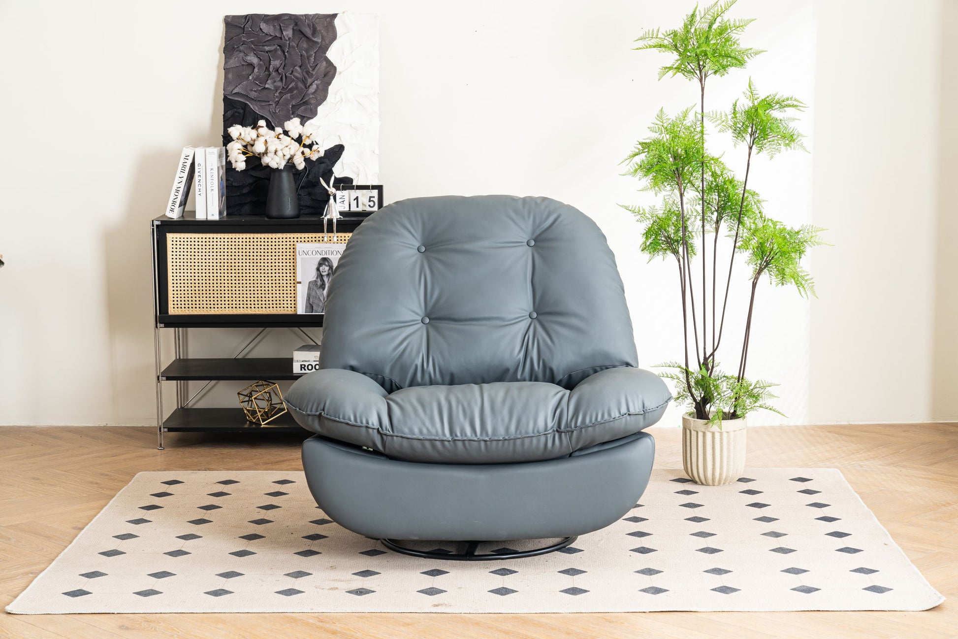 A modern Power Recliner Swivel Glider with USB charger and Bluetooth music player sits on a light rug with black diamond patterns, near a black cabinet with books, decor, and a potted plant. The bright setting feels cozy.