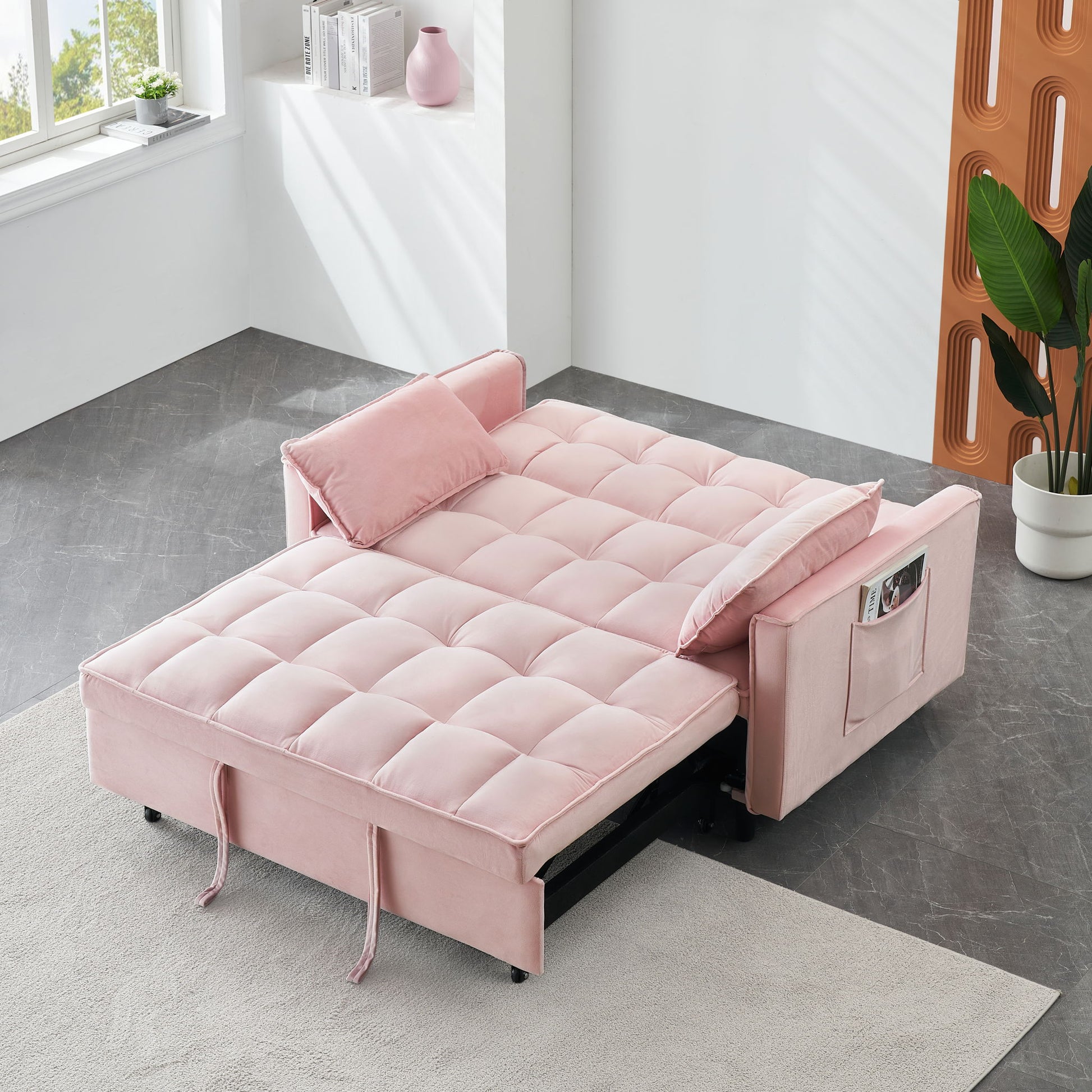 The Modern Velvet Sofa is a 3 in 1 convertible pull-out bed with tufted upholstery, matching pillows, side pockets for magazines, perfect for a bright living room with plants and decorative shelves.