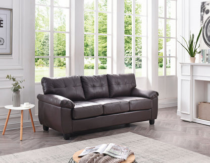 The Comfortable Sofa, in dark brown leather, is featured in a bright living room with large windows and modern decor. A small side table displays a cup and vase, while a round coffee table in front holds magazines.