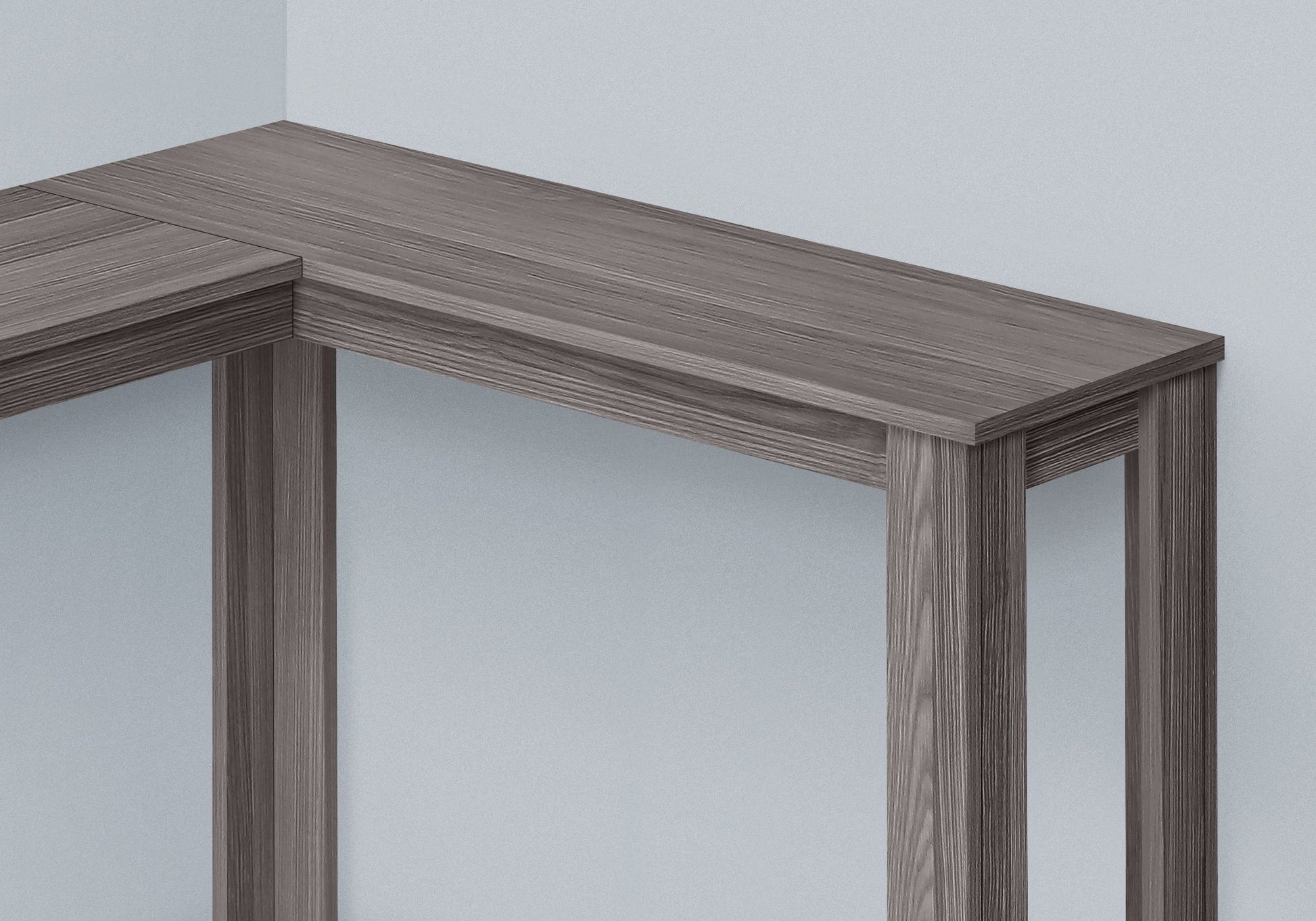 The Corner Accent Console Table For Entryway features a unique contemporary design with clean lines and a grayish-brown finish, neatly positioned in the corner of a light-colored room for a modern, minimalist look.