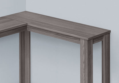 The Corner Accent Console Table For Entryway features a unique contemporary design with clean lines and a grayish-brown finish, neatly positioned in the corner of a light-colored room for a modern, minimalist look.