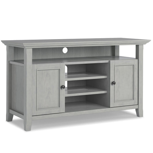 The Amherst - TV Media Stand, Handcrafted, features light gray wood, a flat top, two side cabinet doors, three open center shelves, an open back panel with a cable cutout, and slightly tapered legs.