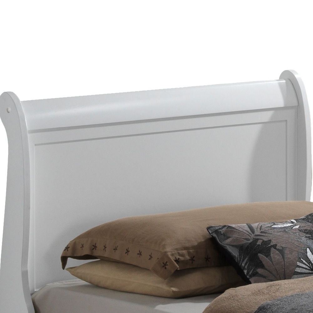 A Panel Sleigh Bed with a white wooden headboard is adorned with brown and tan pillows, including one with a floral pattern, resting against it.