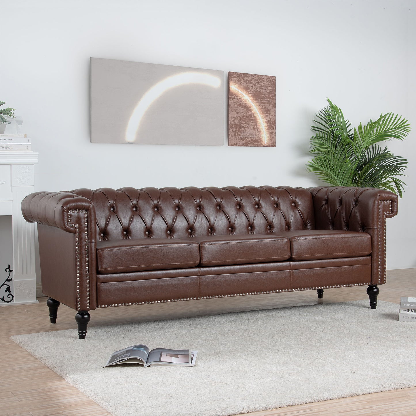A Traditional Square Arm Removable Cushion 3 Seater Sofa in brown leather sits on a light rug in a modern living room featuring a plant, fireplace, abstract wall art, and an open magazine on the floor.