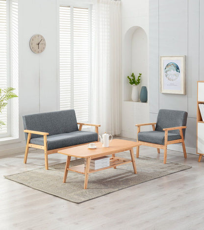 The Bahamas - Living Room Set features light wood floors, a gray loveseat, matching armchair, wooden coffee table, wall art, vases with greenery, and large windows with white blinds and sheer curtains for a modern look.