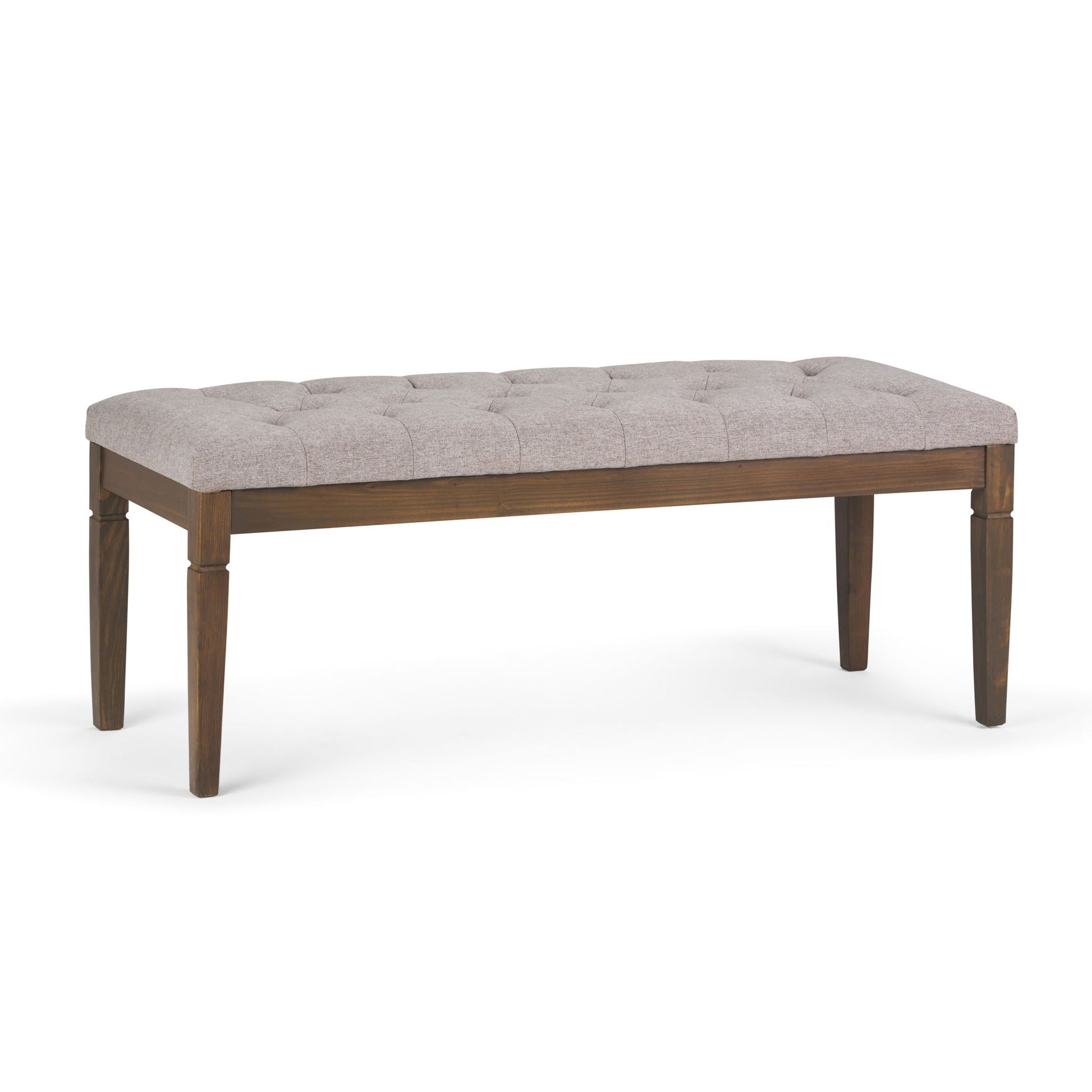 The Waverly Upholstered Tufted Ottoman Bench features four wooden legs and a light gray tufted seat, displayed against a plain white background.
