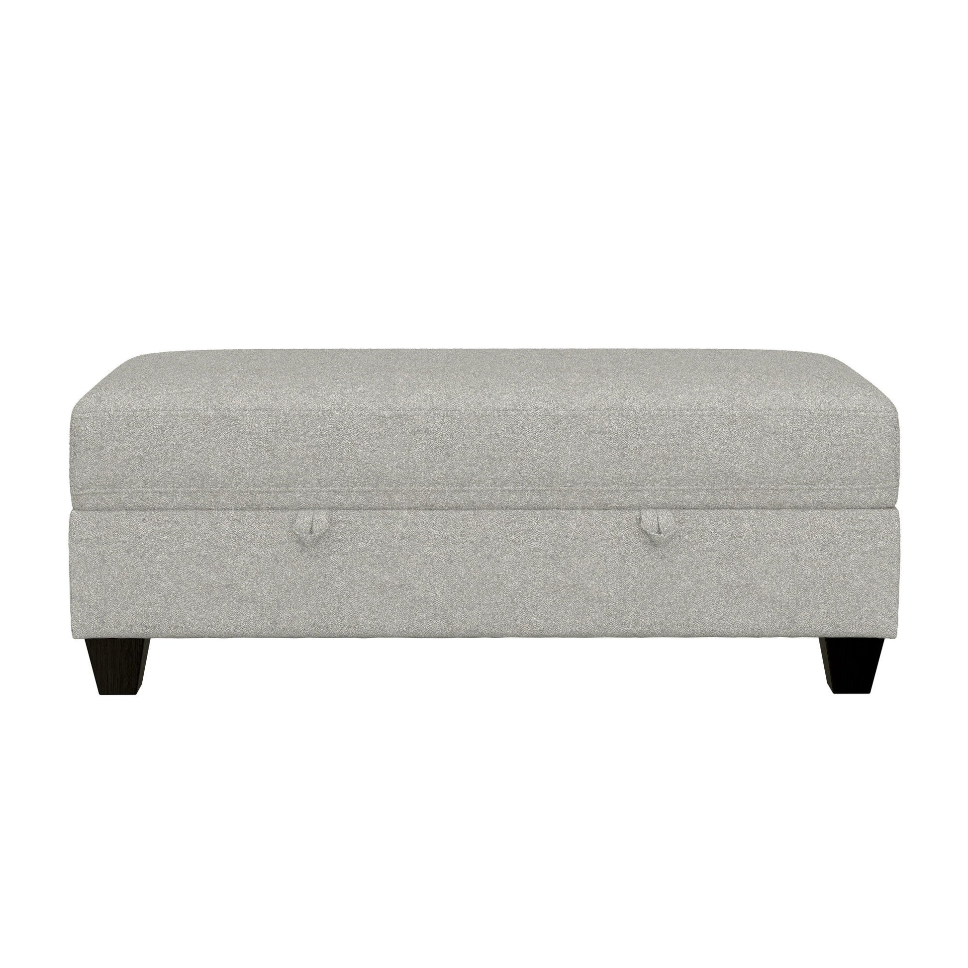 The Drason Storage Ottoman is rectangular, light gray, and upholstered, featuring short dark wooden legs and two small fabric handles on the front.