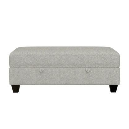 The Drason Storage Ottoman is rectangular, light gray, and upholstered, featuring short dark wooden legs and two small fabric handles on the front.