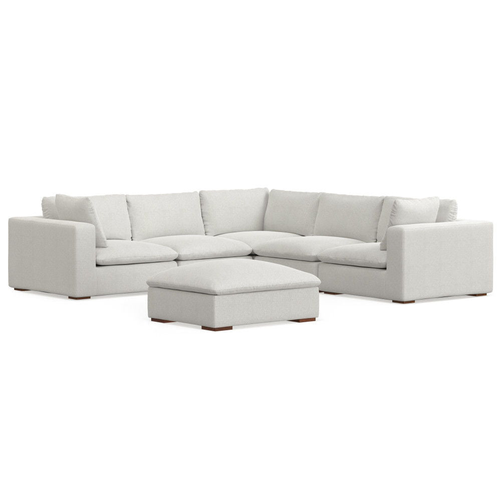 The Jasmine - Handcrafted Sofa and Ottoman is a modern, light gray sectional with thick cushions and a matching square ottoman, both featuring low-profile wooden legs.
