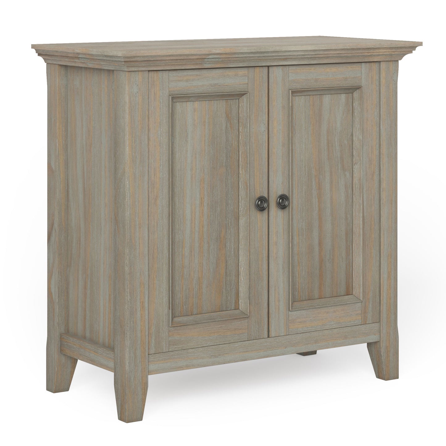 The Amherst - Handcrafted Low Storage Cabinet features a light, weathered wood finish, two paneled doors with round metal knobs, and short, angled legs.