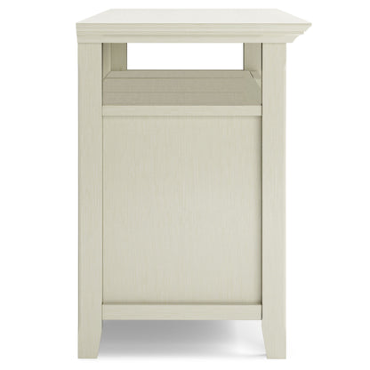 A side view of the Amherst TV Media Stand, handcrafted from light wood with a simple rectangular design, straight legs, a smooth finish, and a shelf below the tabletop.