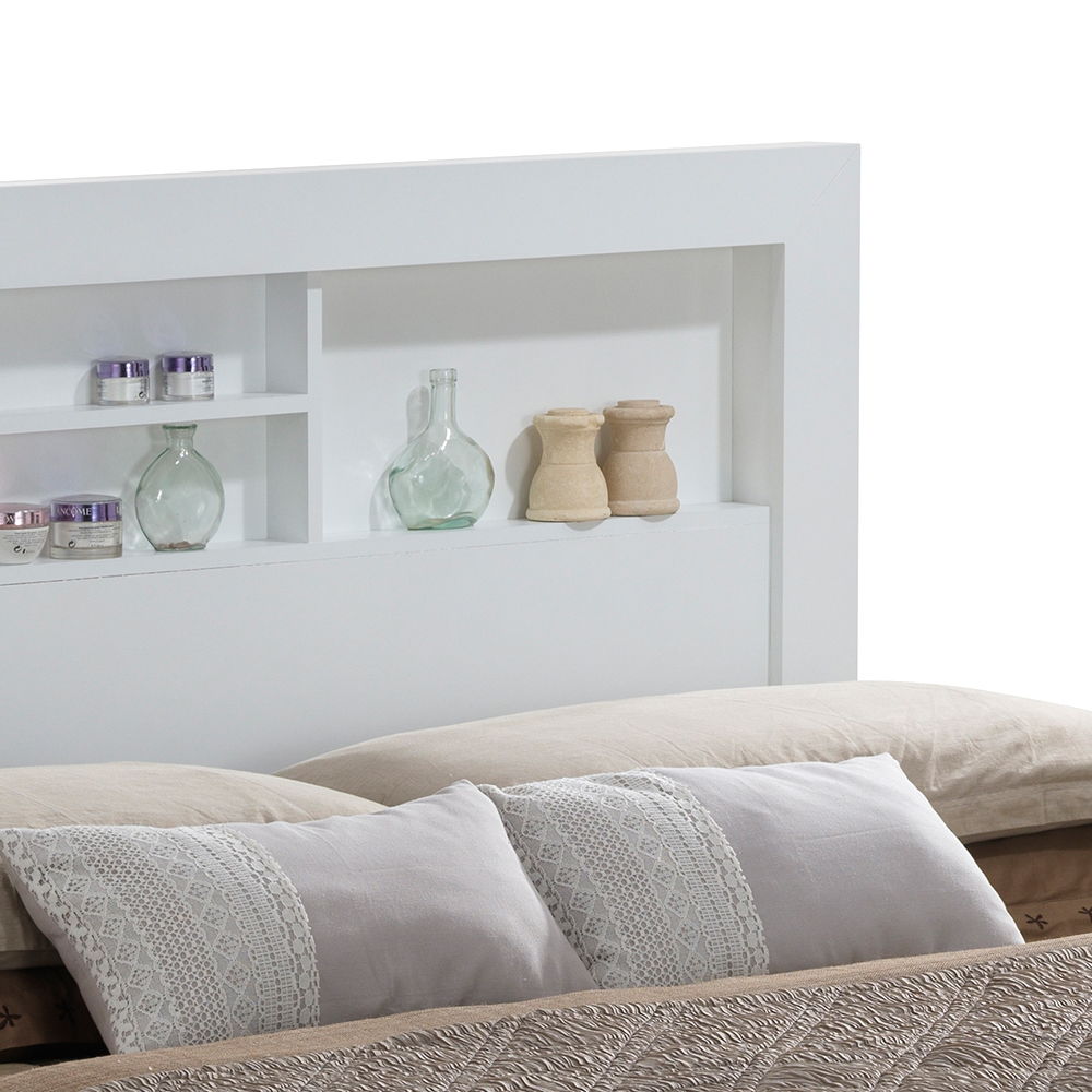 A close-up of the Bed With Transitional Design Stylish, featuring a modern white headboard with built-in shelves holding glass bottles, jars, and wooden containers, set behind a neatly made bed with beige and gray patterned pillows.