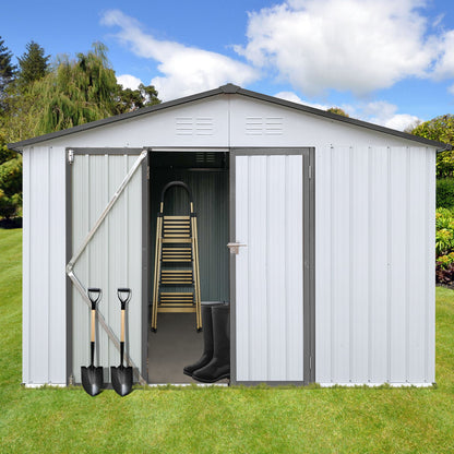 A 10' x 12' Garden Sheds Outdoor Storage Shed with open double doors displays a ladder and black rubber boots inside, two shovels leaning on the left door. The shed is set on a grassy lawn with trees behind it.