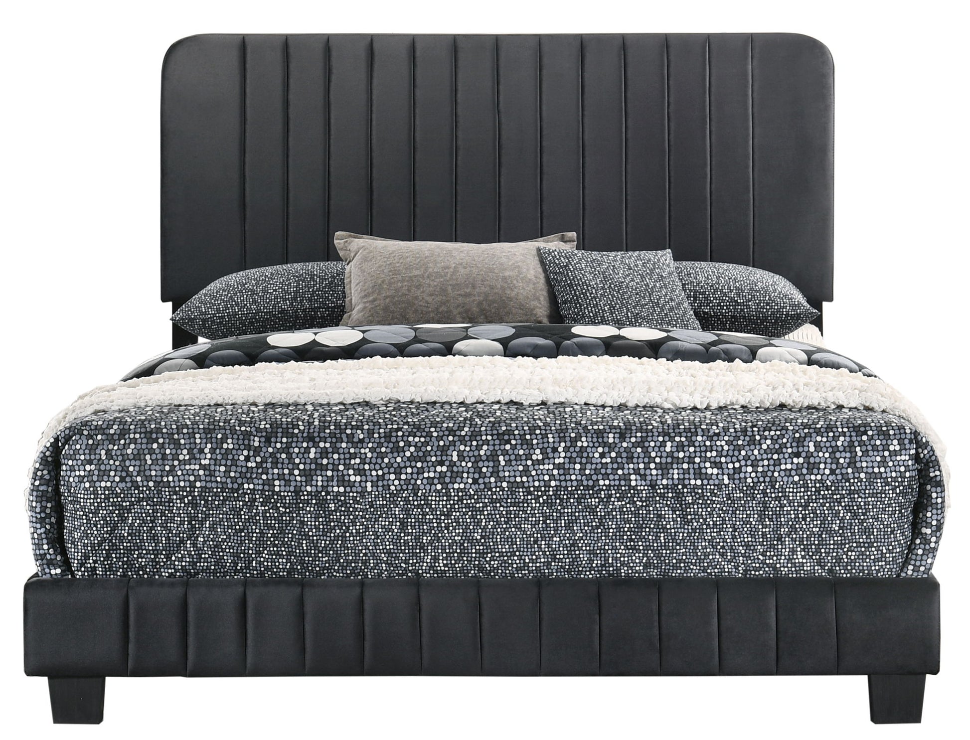 The Lodi - Bed is a modern black upholstered bed featuring a tall vertical-stitched headboard, dressed in black, white, and gray bedding with textured blankets and three decorative pillows.