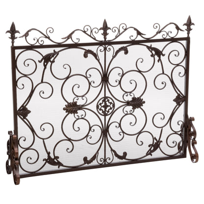 The Darcie - Wrought Fireplace Screen features an ornate black metal design with scrollwork, leaf accents, and fleur-de-lis finials, standing upright on two curved legs against a white background.