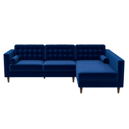 The Christian Mid-Century Modern Design Sectional Sofa features blue velvet upholstery, tufted back cushions, wooden legs, two bolster pillows, and a right-facing chaise lounge.