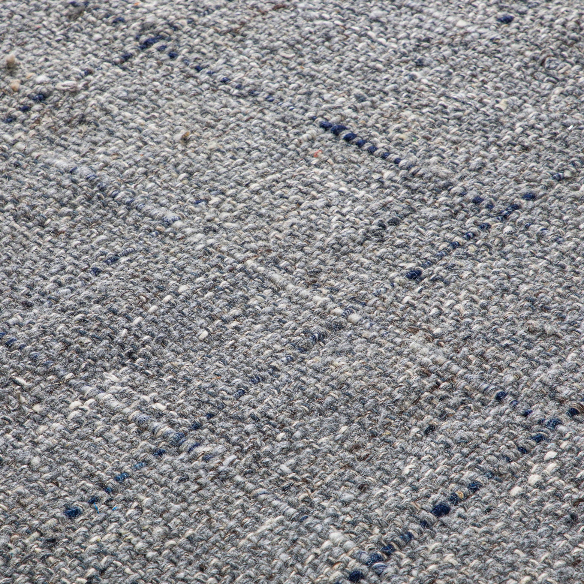 Close-up of the Tenney Handcrafted Area Rug, featuring textured woven gray fabric with a subtle grid pattern and visible yarn threads.