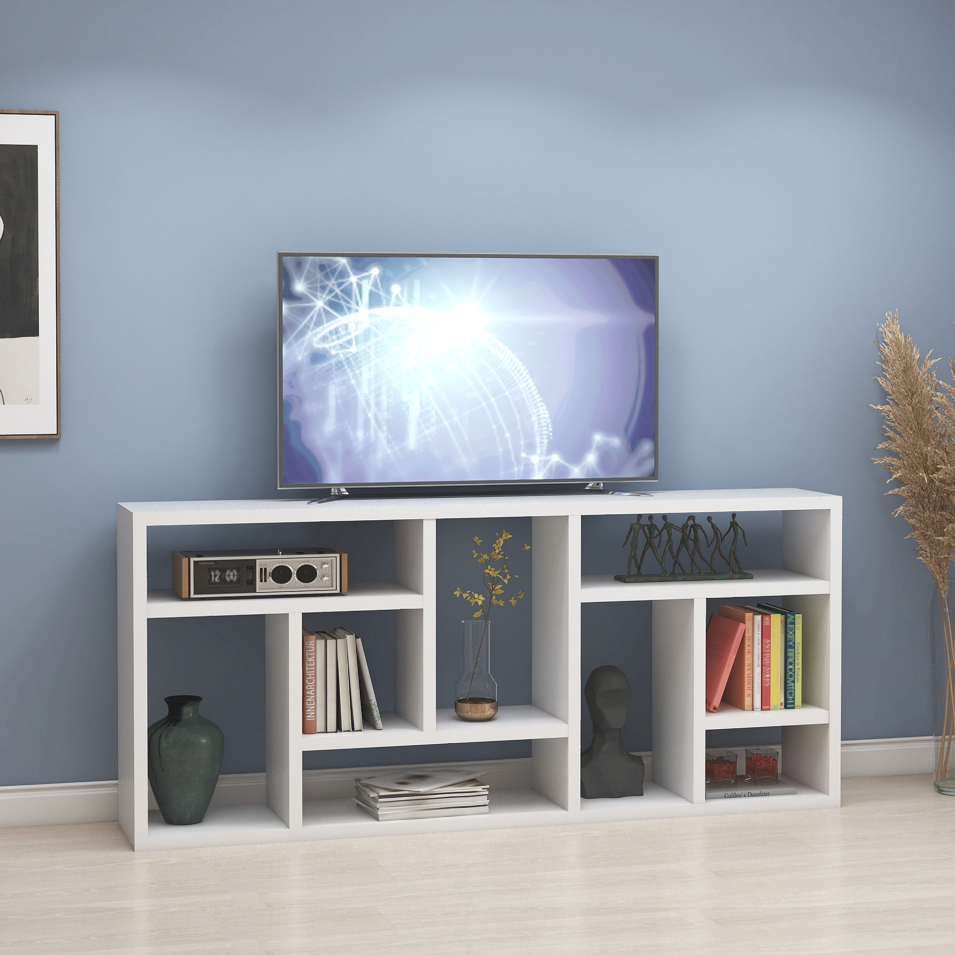 The Versatile Display Cabinet in white holds a flat-screen TV, books, vases, and decor against a light blue wall with artwork and dried plants nearby on a light wood floor.