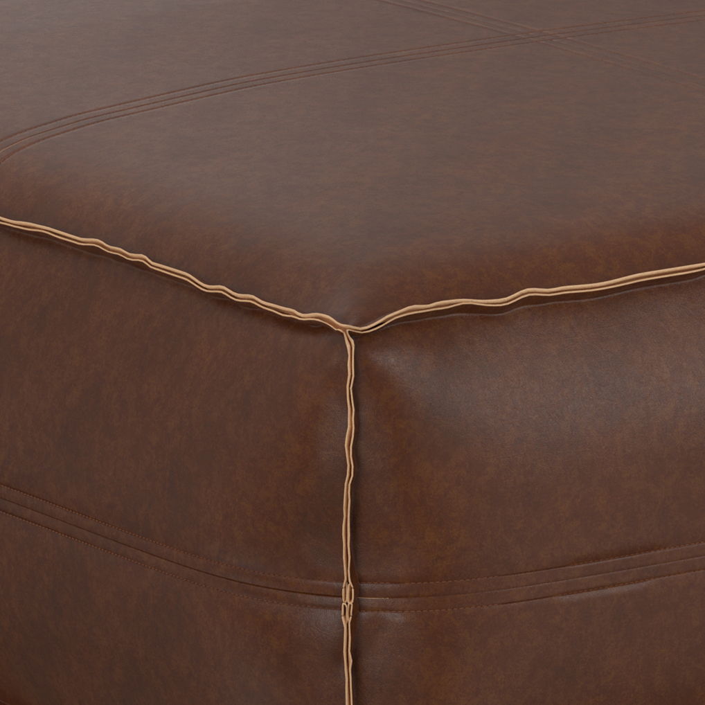 Close-up of the Brody Large Square Coffee Table Pouf corner, highlighting its brown leather finish with detailed stitching and contrasting thread along the seams.