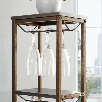 A close-up of the 11 Bottle Wine Bakers Rack, featuring a hanging wine glass holder with four upside-down glasses, wood and metal shelves, a white planter on top, and a window in the background.