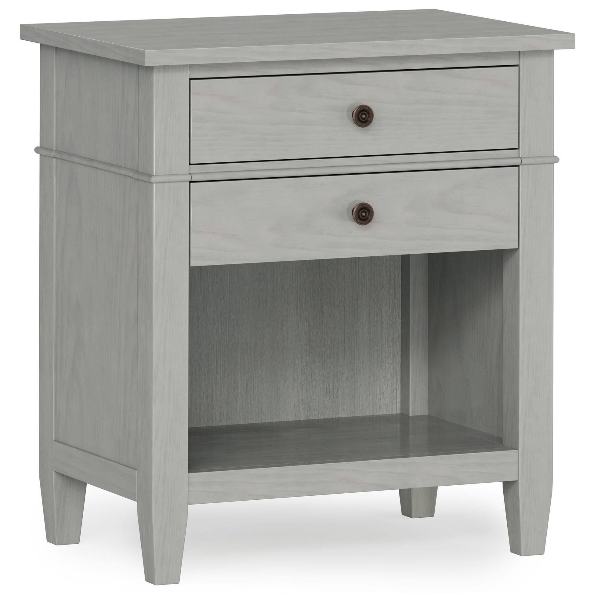 The Carlton Bedside Table is a handcrafted, light gray wooden nightstand with two drawers featuring round metal knobs, an open lower shelf, and simple tapered legs for a modern, minimalist look.
