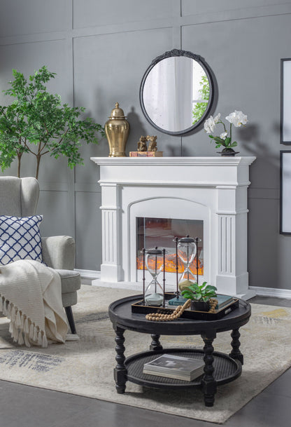 A cozy living room with a white fireplace, the Round Hand Carved Rose Antique Mirror Frame above it, potted plant, armchair with blanket, and a black round coffee table holding decor on a beige rug.