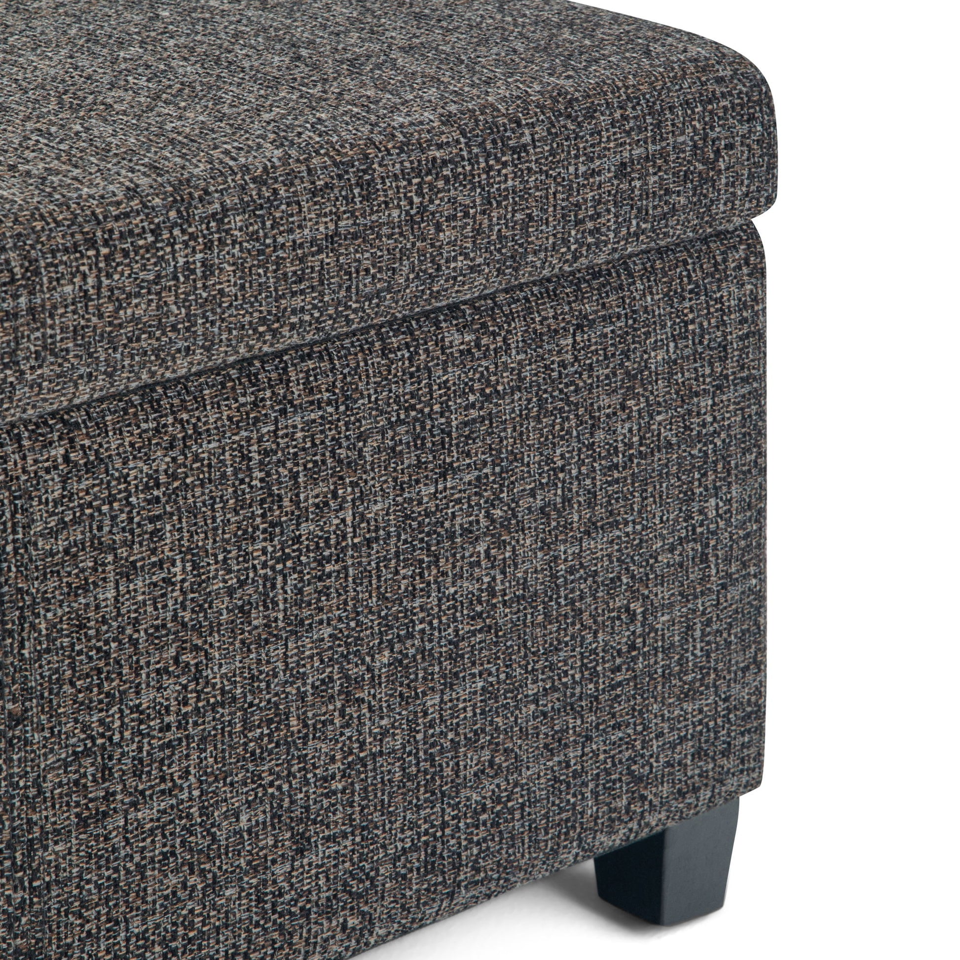 Close-up of the corner of the Avalon Storage Ottoman Bench in dark gray, featuring textured fabric upholstery and short black wooden legs, shown against a white background.