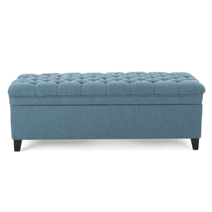 The Juliana Storage Ottoman features a blue upholstered design, a tufted cushion top, and short birch legs, shown against a white background.