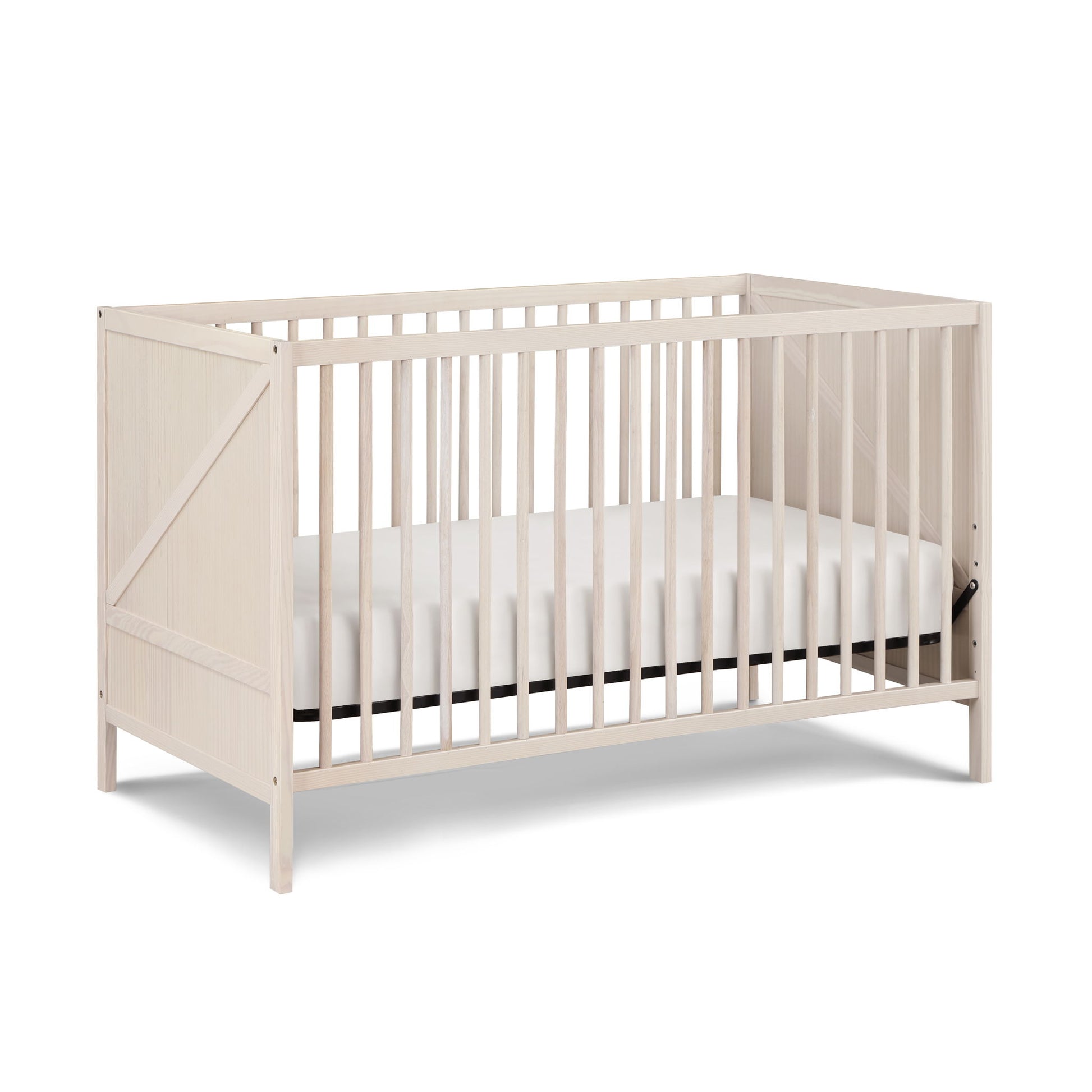 The Pixie Zen 3-in-1 Crib in Walnut features a light wood finish, slatted sides, a simple modern design, white mattress, four legs, and angled panels on the short ends.