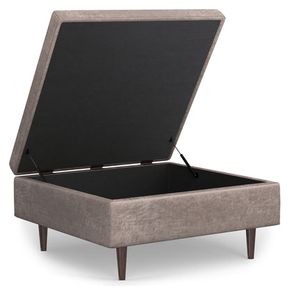 The Shay Large Square Coffee Table Storage Ottoman features beige upholstery, a hinged lid revealing empty storage, and four tapered wooden legs in a mid-century style.