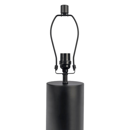 The Aura Table Lamp features a black and white block base, a cylindrical body, an on/off switch, and a harp to support a future lampshade. Lampshade not included.