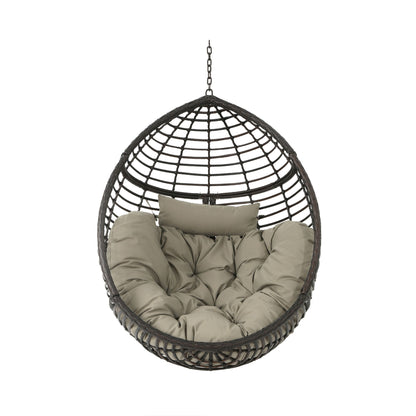 The Hanging Basket Chair With Metal Frame And Seat Cushion is a round black rattan chair with a suspension chain, thick tufted beige cushions, and a matching headrest for a cozy, inviting look.