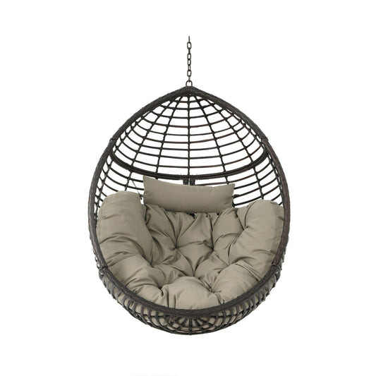 The Hanging Basket Chair With Metal Frame And Seat Cushion is a round black rattan chair with a suspension chain, thick tufted beige cushions, and a matching headrest for a cozy, inviting look.