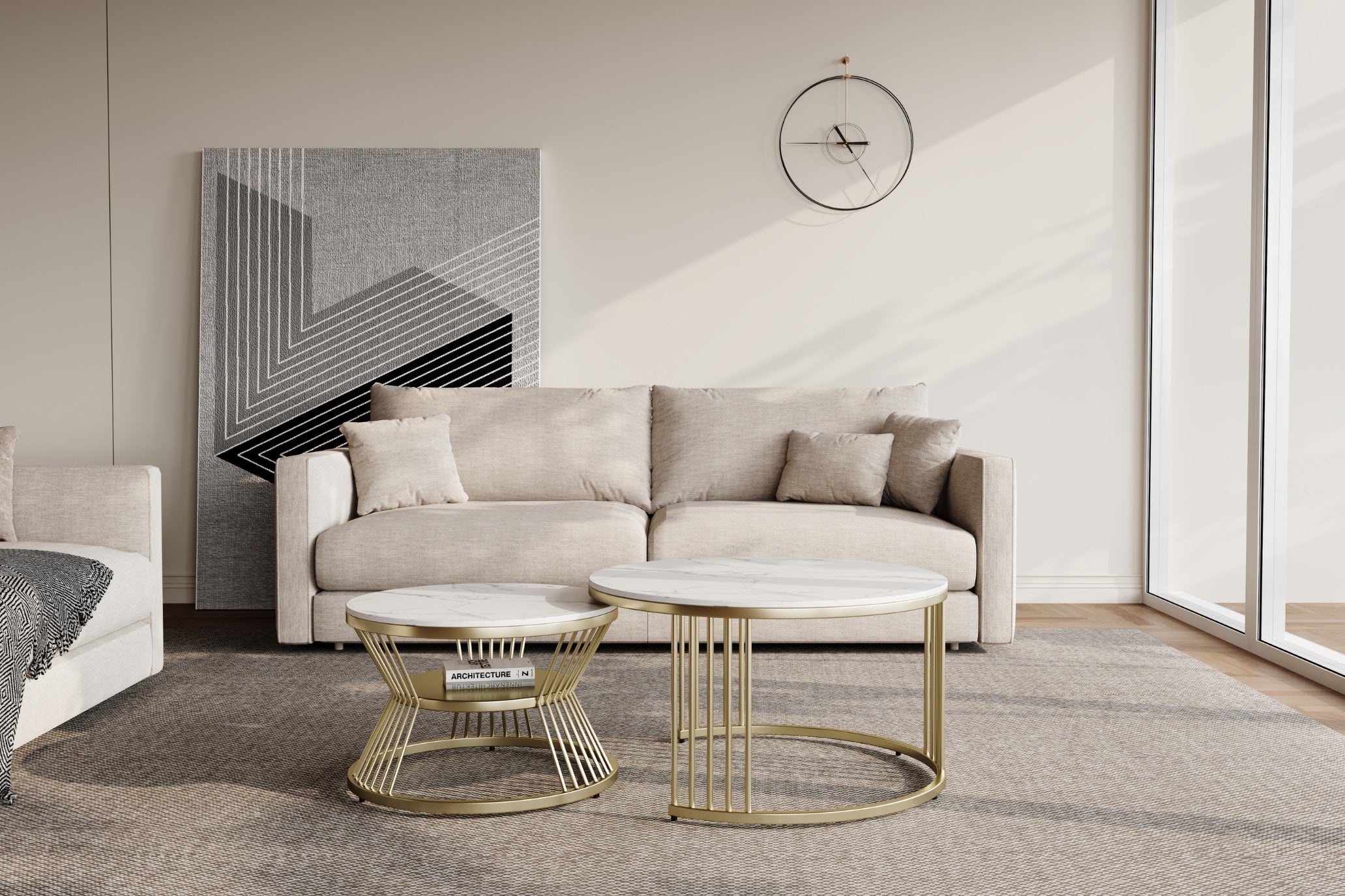 Minimalist living room with a beige sofa adorned with three cushions, a geometric artwork on the wall, and two round marble-top coffee tables with gold frames. A large window lets in natural light, illuminating the neutral-toned decor.