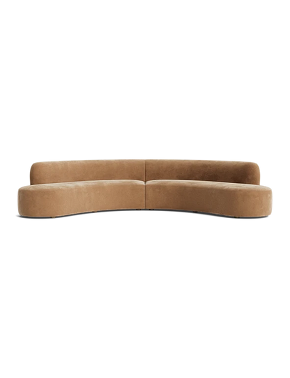 Cara Sectional Sofa in a curved camel shade features a modern, minimalist design composed of two sections. It offers a clean, smooth finish with low-profile backrests, perfect for contemporary living spaces. The backdrop is plain black.