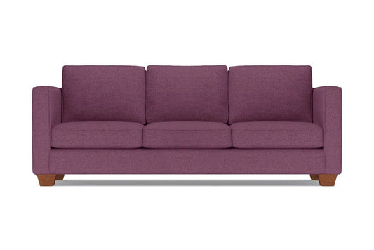 The Catalina Sofa, a plum-colored three-seater with wide armrests and wooden legs, is set against a plain white background. It features three plush seat and back cushions.