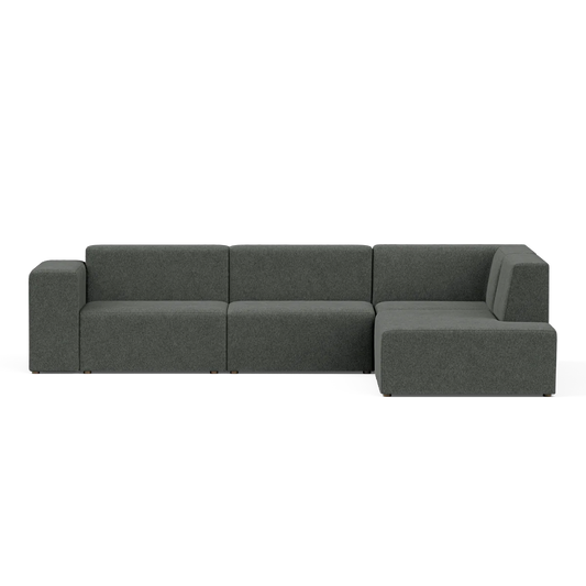 A contemporary Four-Seater Form Sectional in a dark green hue, showcasing clean lines and a minimalist aesthetic, placed against a plain black backdrop. The sectional includes three main sections, featuring an extended right-side chaise.
