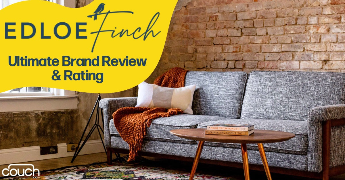 A cozy living room features a gray sofa with orange and white cushions and a throw blanket. A wooden coffee table holds a book. The wall has exposed bricks. Text reads: "Edloe Finch Ultimate Brand Review & Rating" with a bird icon.