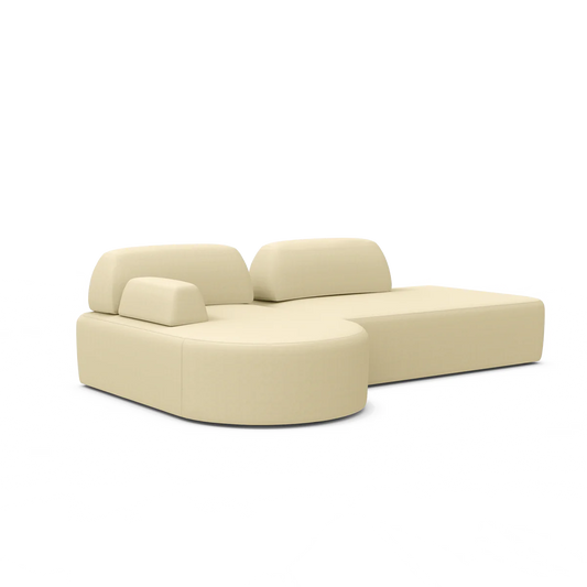 The Magna Preconfigured Sectional is a modern beige L-shaped sofa with smooth cushions, a rounded end, and adjustable headrests.