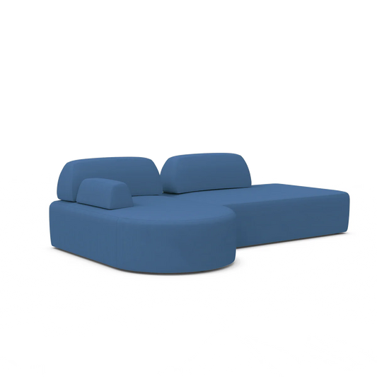 The Magna Preconfigured Sectional is a contemporary blue sectional sofa with a distinctive curved design, featuring multiple cushions and a chaise lounge extension on the right side. Its minimalist style stands out against a plain white background.