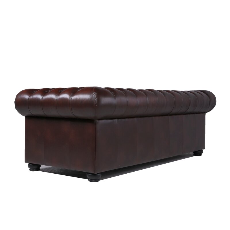 The Birch Lane Freddie 95'' Leather Sofa, seen from the back and side, showcases deep button-tufted detailing, rolled arms, and a plush, rectangular design on short legs. The dark brown leather has a smooth, polished finish.