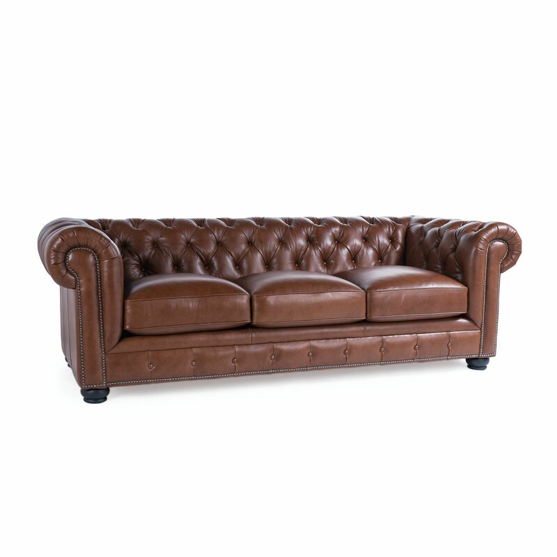 The Birch Lane Freddie 95'' Leather Sofa, made with brown leather and showcasing a Chesterfield design with tufted back and arms, features three seat cushions and nailhead trim, set against a white background.