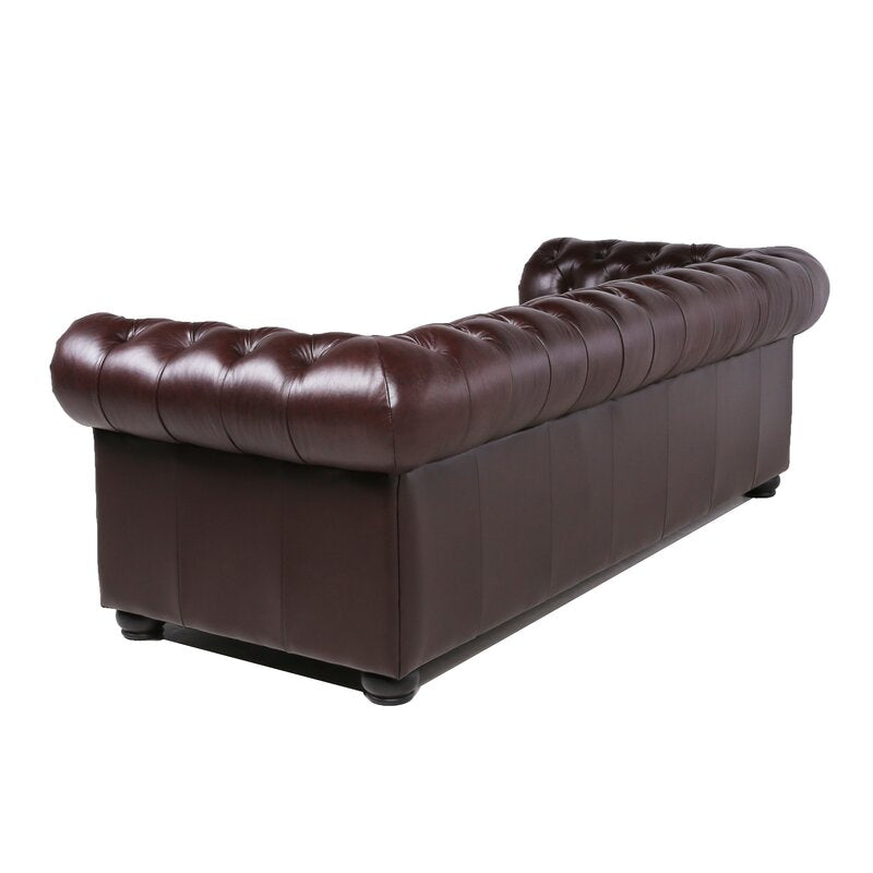 The Birch Lane Freddie 95'' Leather Sofa, a dark brown leather Chesterfield design, is shown from the back. It features deep button tufting and rolled arms, set against a plain white background.