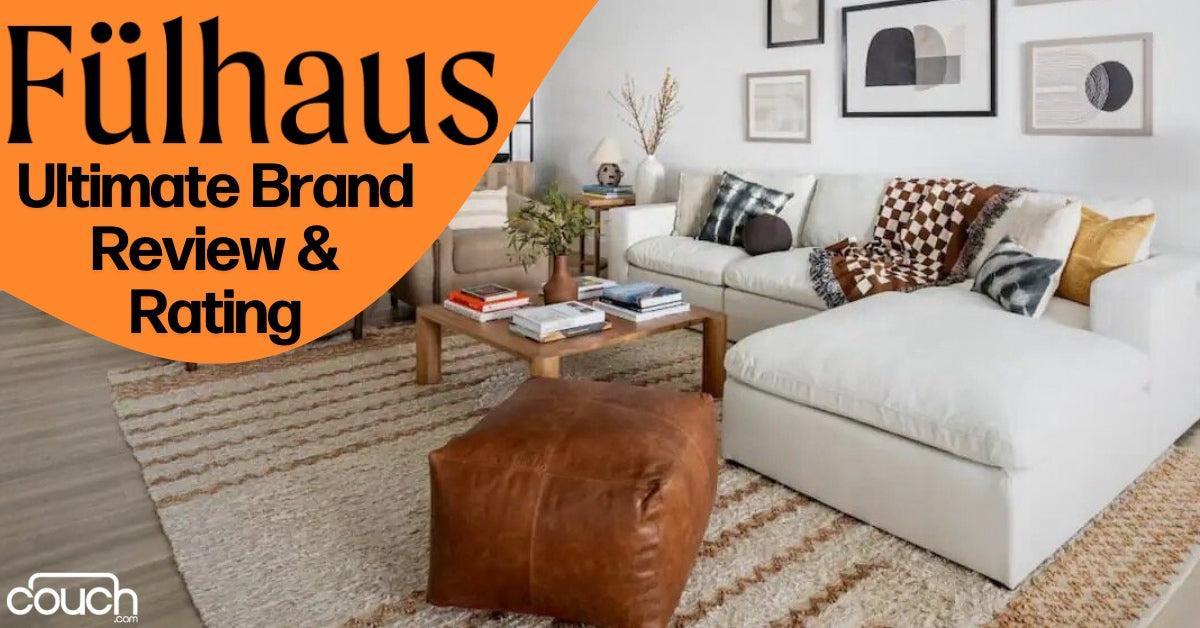 A cozy living room with a white sectional sofa, various patterned pillows, a wooden coffee table with books, and a large brown pouf. The walls have modern art, and a woven rug covers the floor. Text reads "F√ºlhaus Ultimate Brand Review & Rating.